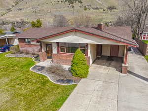 View of front of house featuring concrete driveway, roof with shingles, a front lawn, an attached carport, and brick siding