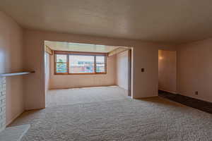 Carpeted empty room featuring baseboards and a textured ceiling