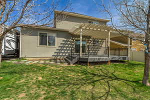 Rear view of house featuring a pergola, a yard, fence, stucco siding, and a wooden deck
