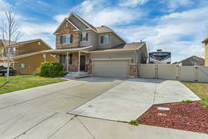 Craftsman house with concrete driveway, stucco siding, stone siding, and a gate