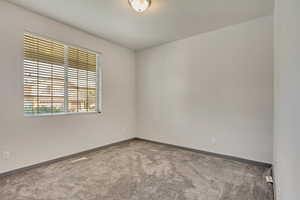 Carpeted spare room featuring baseboards