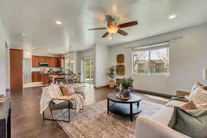 Living room featuring ceiling fan, recessed lighting, baseboards, and dark wood-style floors