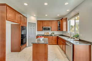 Kitchen featuring glass insert cabinets, recessed lighting, appliances with stainless steel finishes, marble finish floor, and a sink
