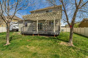 Back of house with stucco siding, a pergola, a fenced backyard, a wooden deck, and a lawn