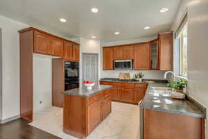 Kitchen with a center island, a sink, dark countertops, stainless steel appliances, and marble finish floor