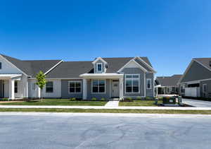 View of front facade featuring board and batten siding, a shingled roof, and a front lawn