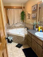 Full bath featuring vanity, tile patterned flooring, and a whirlpool tub