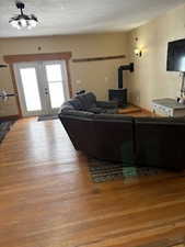 Living room with french doors, a wood stove, and wood finished floors