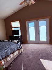 Bedroom with french doors, light colored carpet, multiple windows, and vaulted ceiling