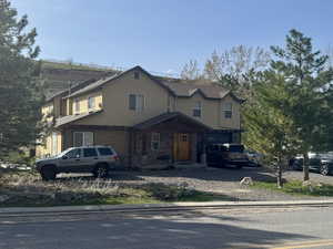 View of front of property featuring driveway, stone siding, a garage, and stucco siding