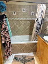 Bathroom featuring tile patterned floors, vanity, and tiled shower / bath