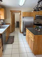 Kitchen with dark countertops, light tile patterned floors, a sink, and appliances with stainless steel finishes