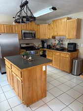 Kitchen featuring a textured ceiling, light tile patterned flooring, dark countertops, and stainless steel appliances