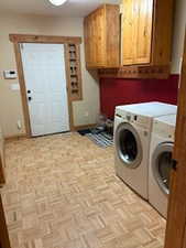 Clothes washing area featuring washer and dryer, baseboards, and cabinet space