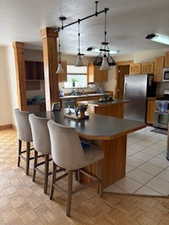 Kitchen featuring dark countertops, decorative light fixtures, a kitchen breakfast bar, and appliances with stainless steel finishes