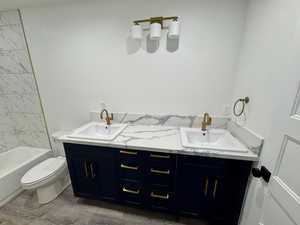 Full bathroom featuring toilet, double vanity, and a sink
