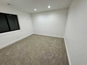 Carpeted empty room featuring baseboards, visible vents, and recessed lighting