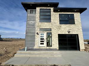 Contemporary house featuring driveway and stone siding