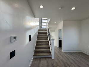 Stairway with recessed lighting, baseboards, and wood finished floors