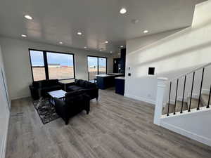 Living room with recessed lighting, stairway, baseboards, and wood finished floors