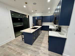 Kitchen featuring a sink, light wood-type flooring, black appliances, and blue cabinets