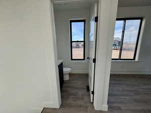 Bathroom featuring toilet, wood finished floors, vanity, and baseboards