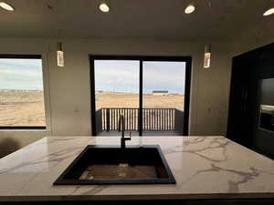 Kitchen featuring recessed lighting, pendant lighting, a sink, and light stone counters