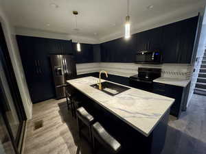 Kitchen with visible vents, stainless steel refrigerator with ice dispenser, a sink, dark cabinets, and black / electric stove