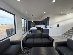 Living area featuring baseboards, recessed lighting, stairway, and light wood finished floors