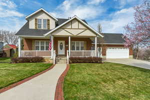 View of front facade with a garage, a porch, driveway, and a front lawn