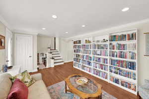 Living area featuring wood finished floors, recessed lighting, ornamental molding, and stairs