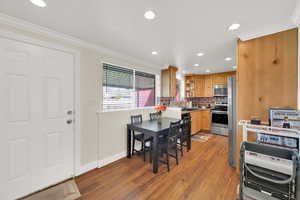 Dining space featuring crown molding, baseboards, light wood finished floors, and recessed lighting