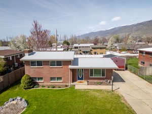 Split level home featuring brick siding, a front lawn, fence, and driveway