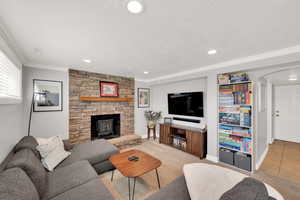 Living area with tile patterned flooring, a textured ceiling, crown molding, a wood stove, and arched walkways