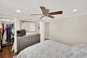 Bedroom with a closet, dark wood-style flooring, a spacious closet, crown molding, and recessed lighting