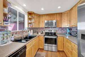 Kitchen featuring light wood-type flooring, a sink, open shelves, and stainless steel appliances