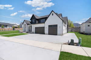 Modern inspired farmhouse with fence, an attached garage, driveway, and a front yard