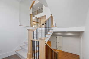 Staircase with baseboards, wood finished floors, and a towering ceiling