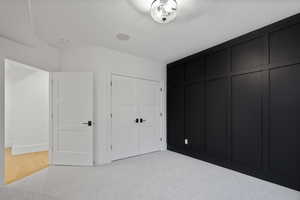 Unfurnished bedroom with baseboards, light carpet, and a closet