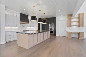 Kitchen featuring open shelves, a spacious island, tasteful backsplash, light wood finished floors, and stainless steel appliances
