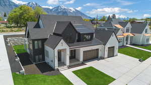 Modern inspired farmhouse featuring covered porch, a front yard, a mountain view, concrete driveway, and stucco siding