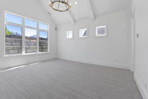Carpeted empty room with an inviting chandelier, baseboards, high vaulted ceiling, and beamed ceiling