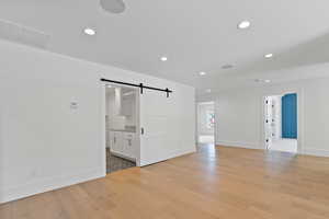 Spare room with visible vents, a barn door, baseboards, and recessed lighting