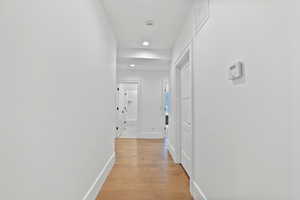Hallway with light wood-style floors, recessed lighting, baseboards, and visible vents