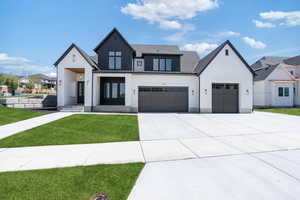 Modern farmhouse style home with an attached garage, driveway, and a front lawn