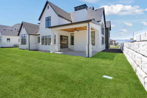 Rear view of property with roof with shingles, a chimney, a patio area, a ceiling fan, and a yard