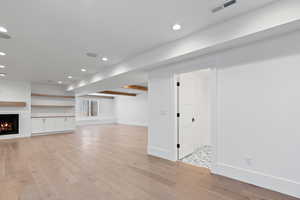 Basement with visible vents, baseboards, recessed lighting, a large fireplace, and light wood finished floors