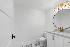Bathroom featuring vanity, baseboards, and toilet