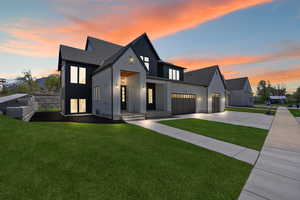Modern farmhouse style home featuring a garage, stucco siding, a lawn, and driveway