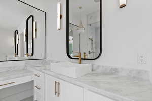 Full bath featuring vanity and a marble finish shower